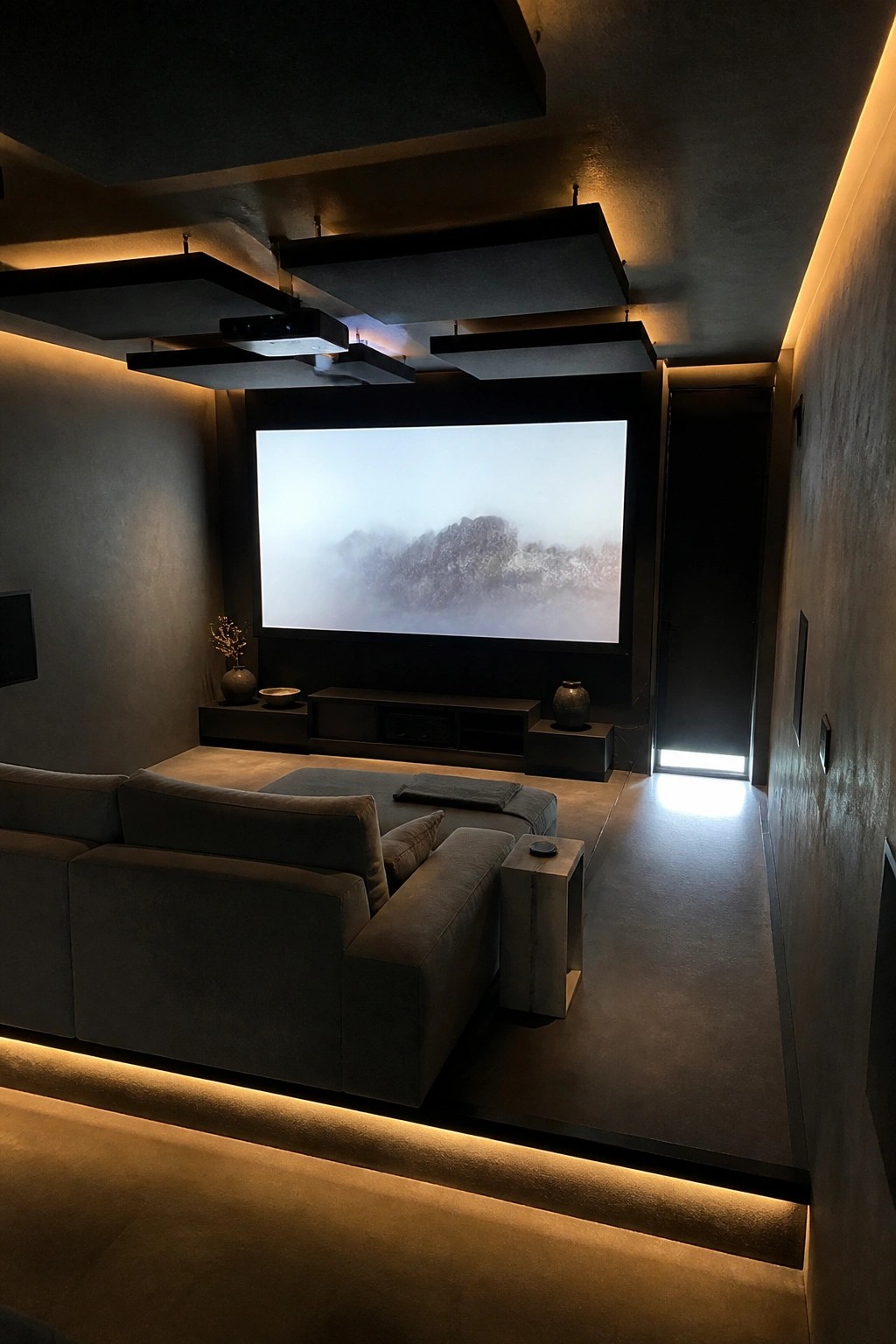 A home theater room showing a large projection screen, dark sectional sofa on a raised platform with under-lighting, and layered ceiling panels with a mounted projector.