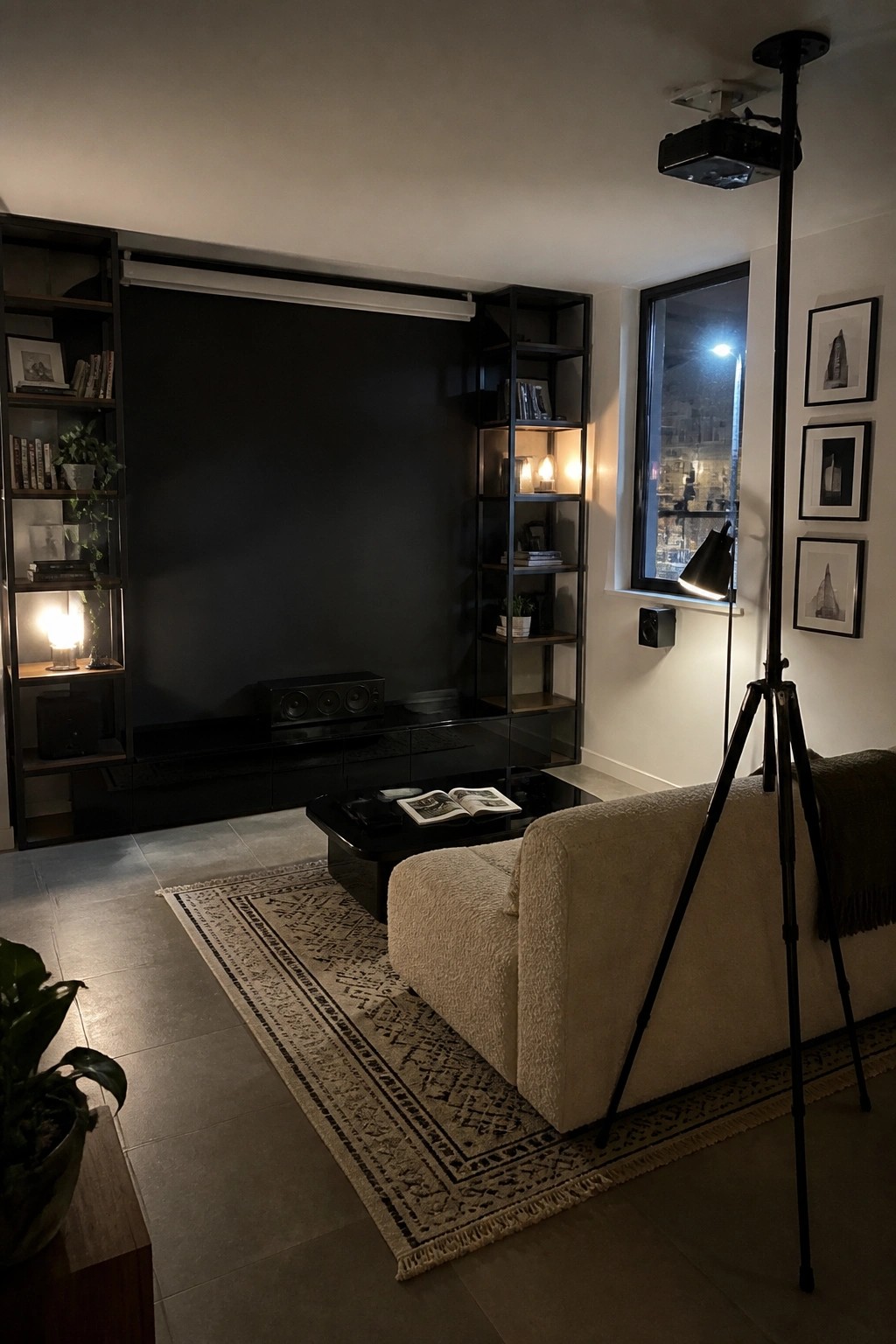 Modern living room with dark shelved wall, tripod projector, beige sofa, and patterned rug.